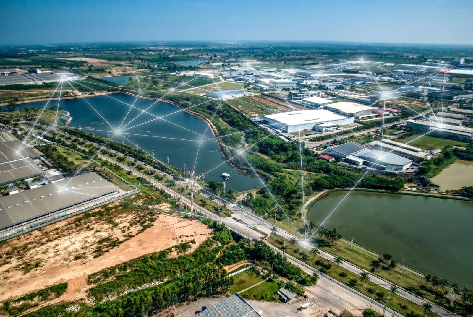 Vista aérea de un área industrial con lagos y zonas verdes conectada por una malla digital de nodos y líneas.