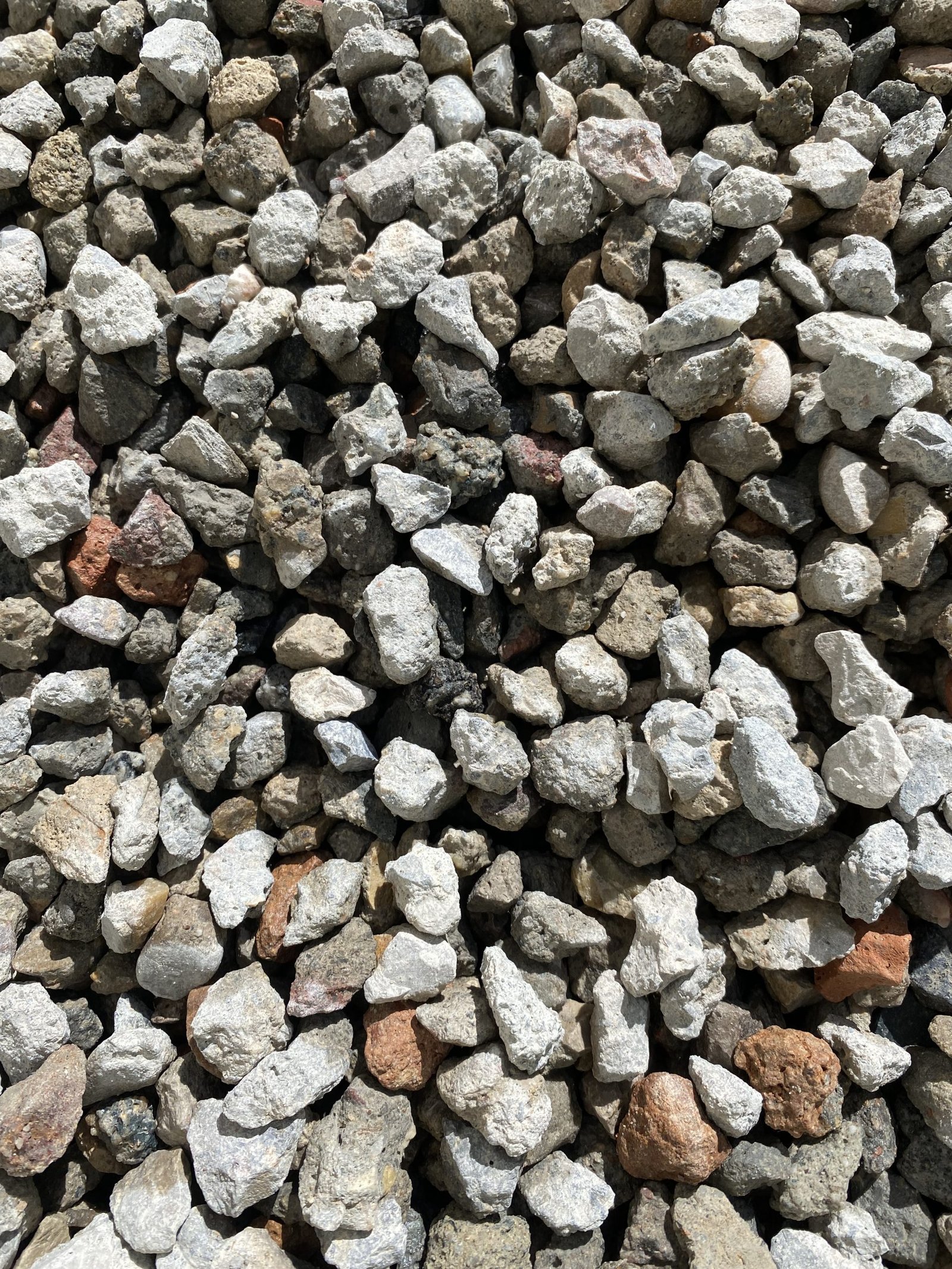 Primer plano de áridos reciclados de obra, con fragmentos de hormigón y piedra de distintos tamaños y tonalidades grises.